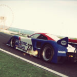 Calsonic Nissan Group C prototype number 23 cornering at Suzuka with Ferris wheel in background and engine afterburner backfire - vintage Le Mans-era endurance racing