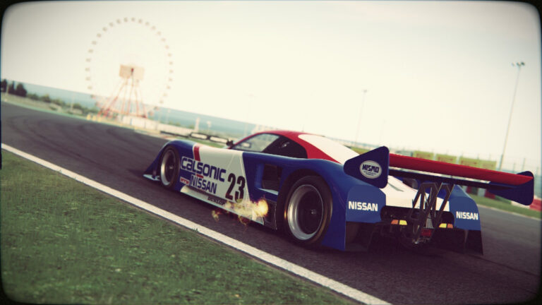 Calsonic Nissan Group C prototype number 23 cornering at Suzuka with Ferris wheel in background and engine afterburner backfire - vintage Le Mans-era endurance racing