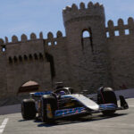 Formula 1 car cornering at the Baku City Circuit with the historic Maiden Tower / city walls visible behind