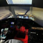 Premium home flight simulator cockpit setup - 737-style overhead, throttle quadrant prominent, projection screens with night cityscape view, HOTAS stick visible, full instrument panel reproduction