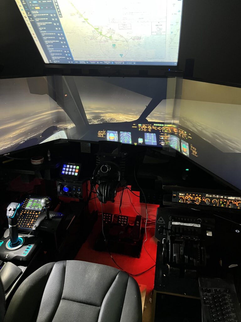 Premium home flight simulator cockpit setup - 737-style overhead, throttle quadrant prominent, projection screens with night cityscape view, HOTAS stick visible, full instrument panel reproduction