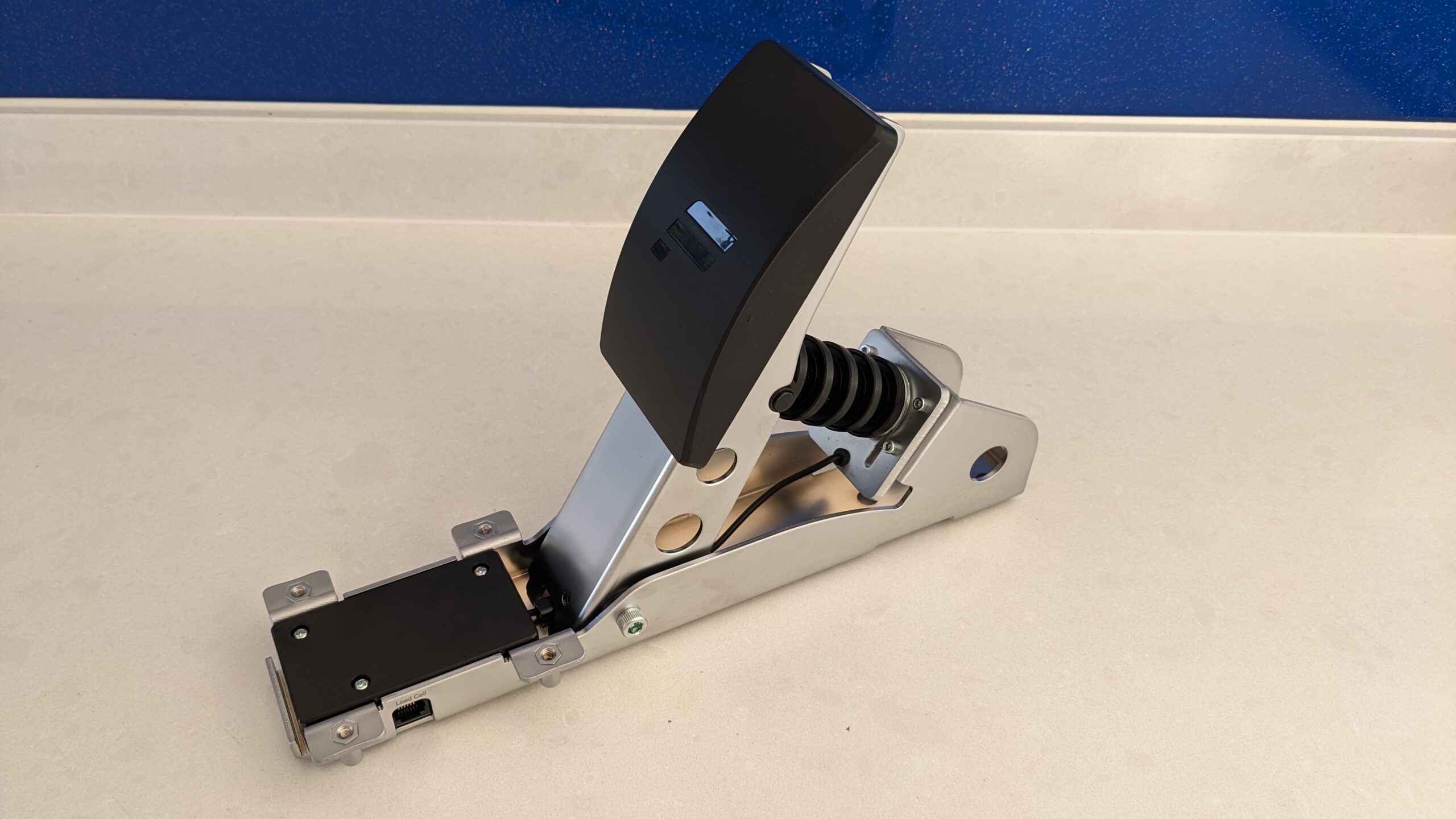 Close-up of a sim racing load cell pedal showing the controller box and RJ12 cable port