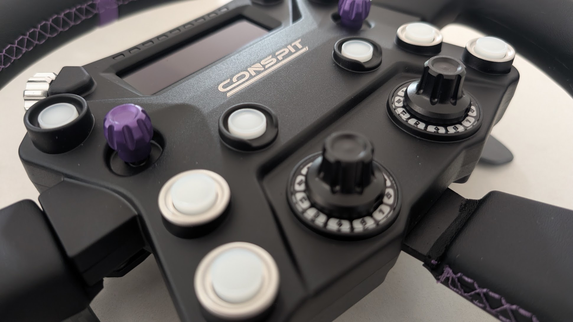 Close-up of the Conspit 310 APEX button box: encoder thumbwheel, purple joystick, 12-position rotary switch and buttons
