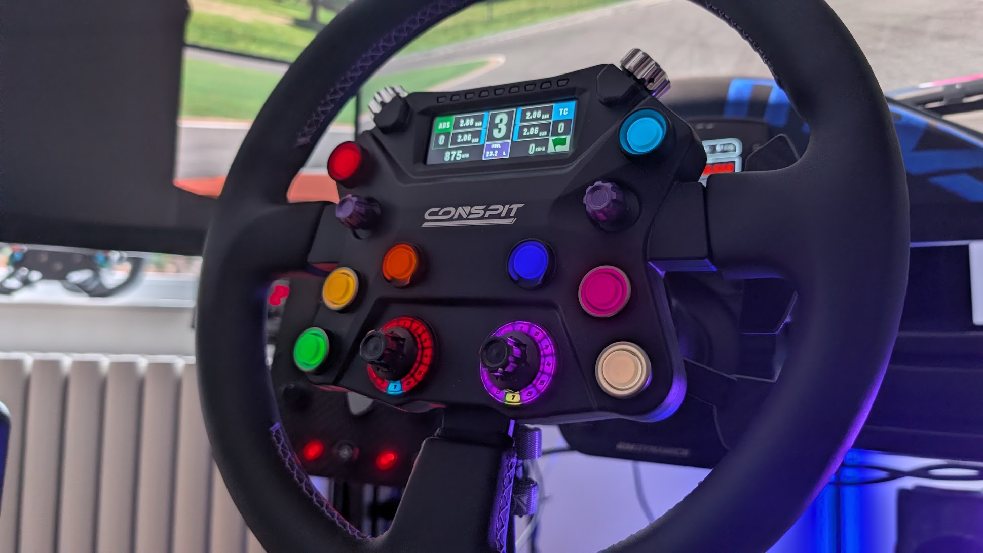 Conspit 310 APEX lit up on the rig: coloured buttons, lit rotary rings and the screen showing 3rd gear