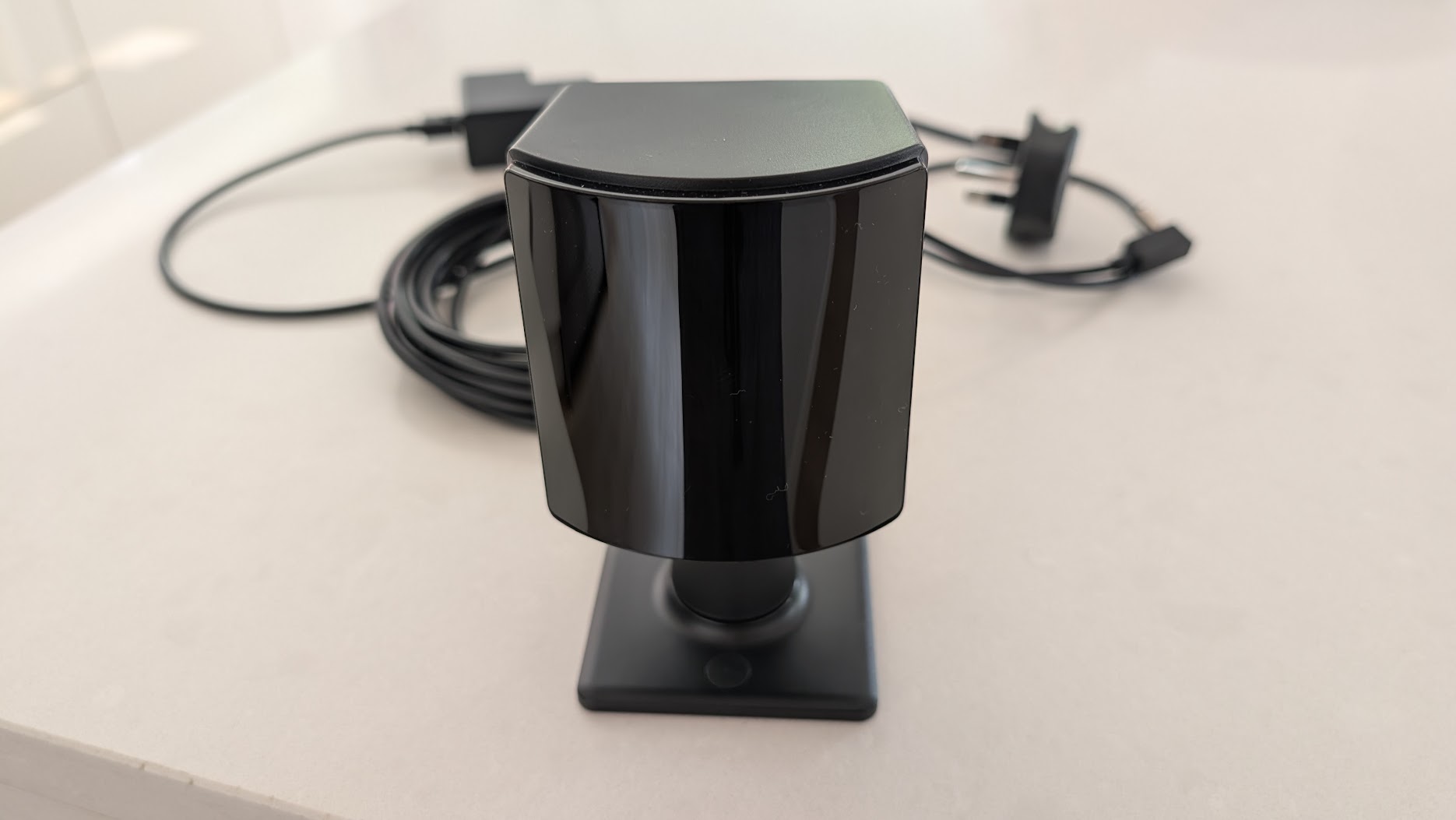 A SteamVR Lighthouse base station on a stand with its cable