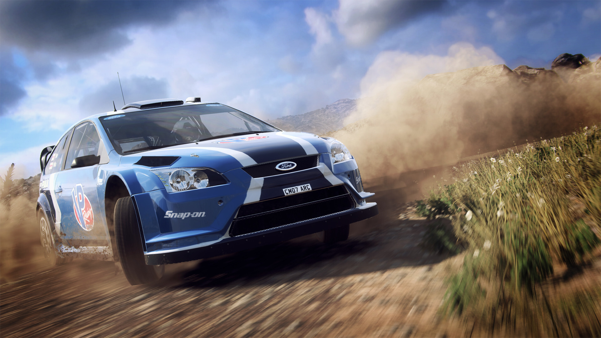 Blue Ford Focus rally car throwing up dust on a dry gravel stage in DiRT Rally 2.0