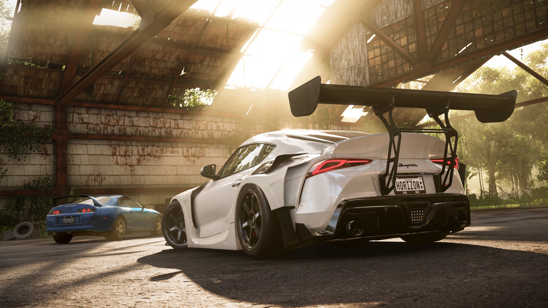 A widebody Toyota GR Supra and a Mk4 Supra in a barn in Forza Horizon 5