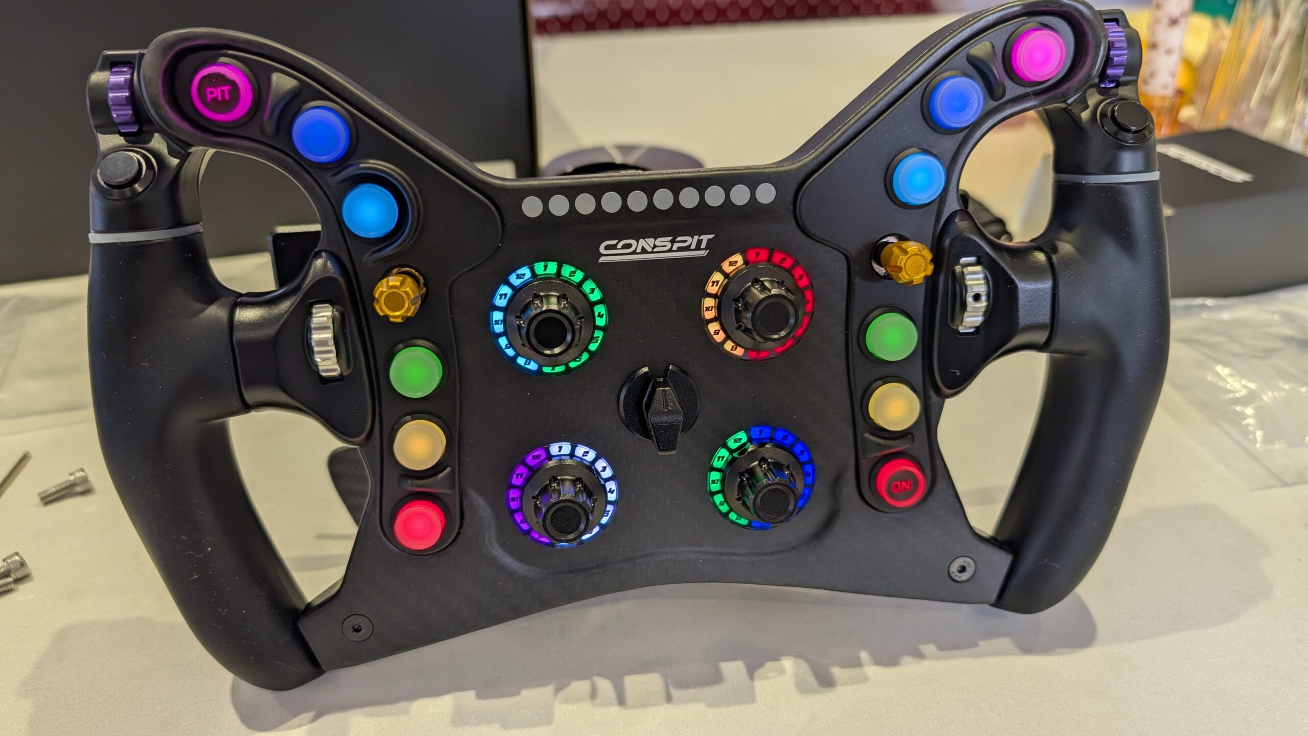 CONSPIT 280 FR lit, close-up of the buttons, rotary switch rings and the gold, silver and purple side controls