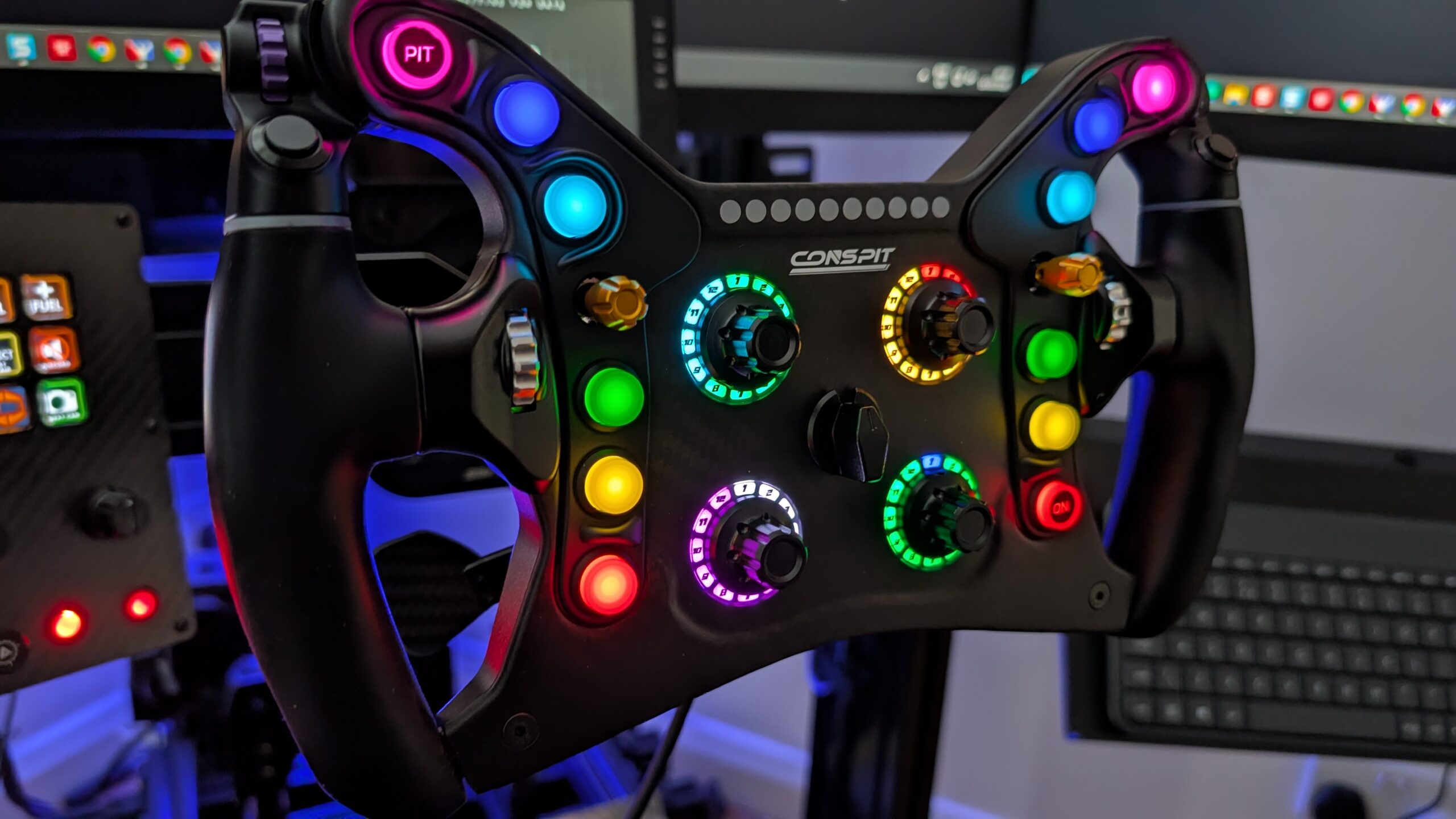 CONSPIT 280 FR lit on a sim rig, angled view with a button box to the left