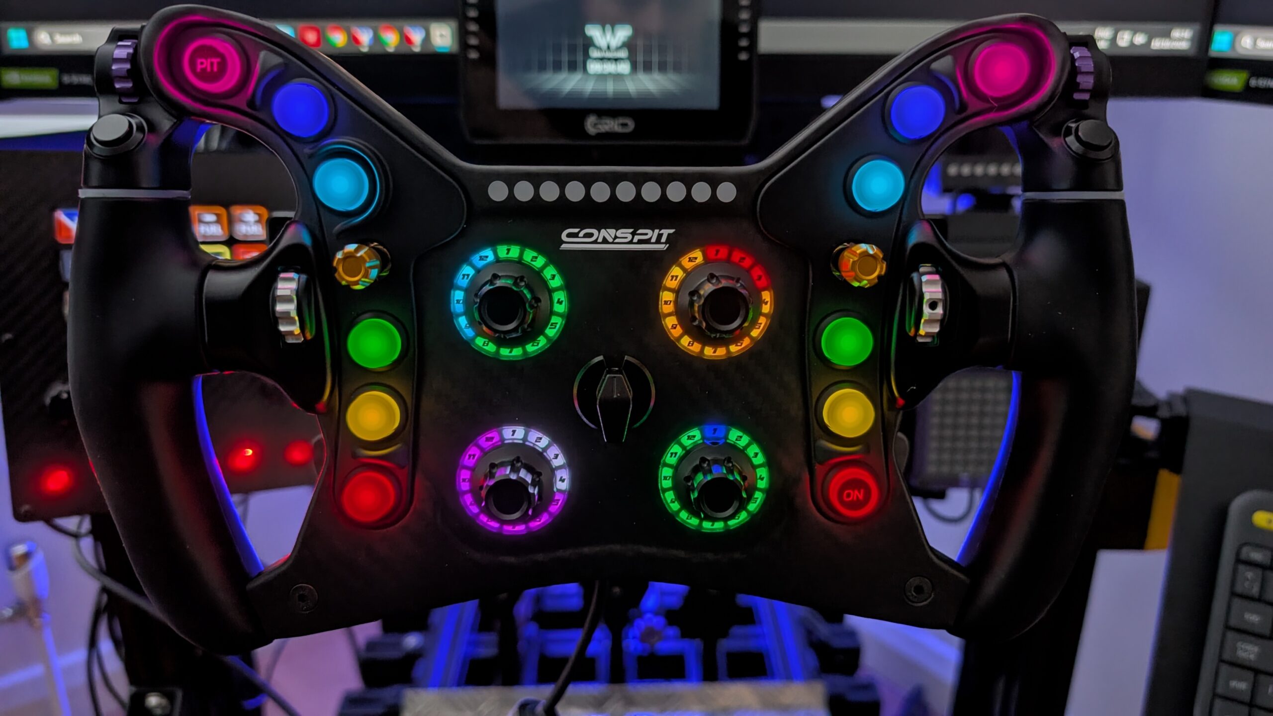 CONSPIT 280 FR steering wheel lit up on a sim rig in front of monitors, buttons and rotary rings glowing