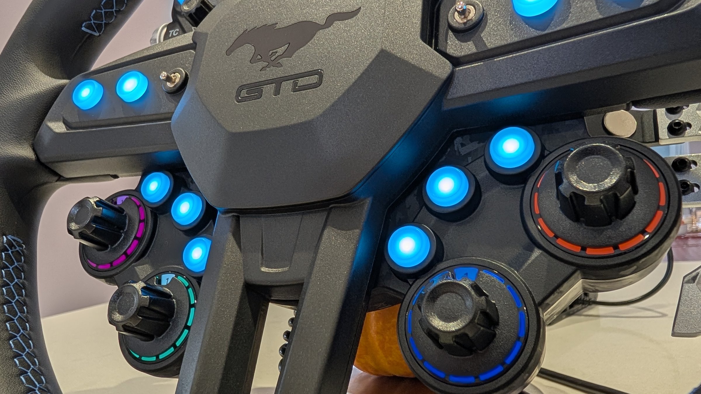 MOZA Mustang GTD wheel centre pad with the Mustang pony and GTD badge, toggle switches, lit buttons and rotary encoders